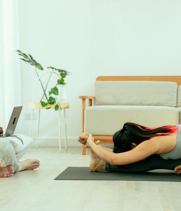 Person doing a light stretching exercise in a bright, minimalist room.