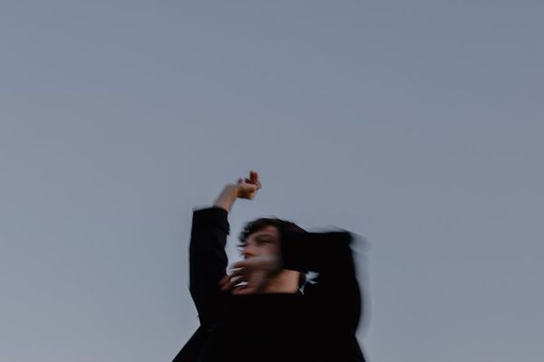 Person in a dynamic but gentle movement pose, blurred background.